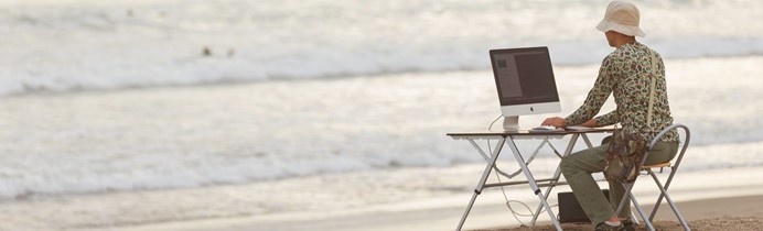 海辺でパソコンをする男性